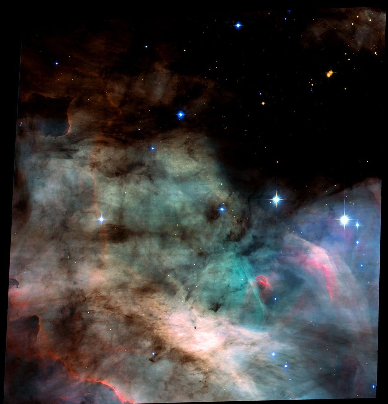 Hubble Space Telescope Advanced Camera for Surveys image of the Omega Nebula (M17), showing a wall of turbulent pink and orange gases sculpted by ultraviolet radiation from nearby young stars.