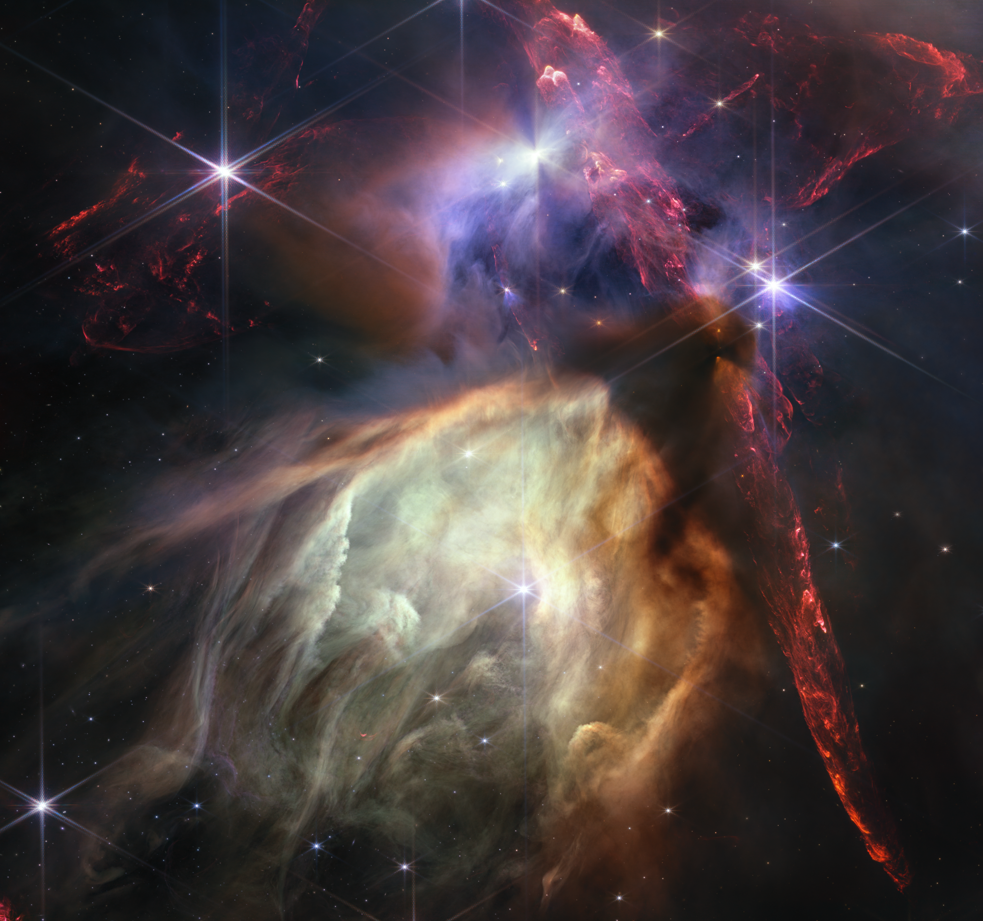 James Webb Space Telescope NIRCam image of the Rho Ophiuchi cloud complex, the closest star-forming region to Earth, showing red bipolar jets and glowing dust caves